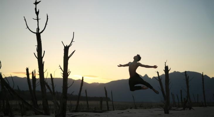 Person jumping in front of mountains and sun