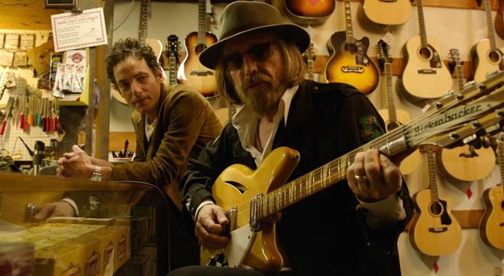 Jakob Dylan watching a musician in a guitar shop