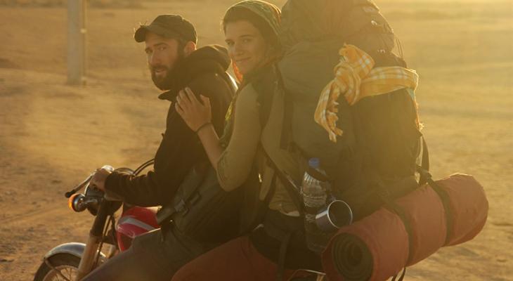 Two people on a motorcycle with a backpack