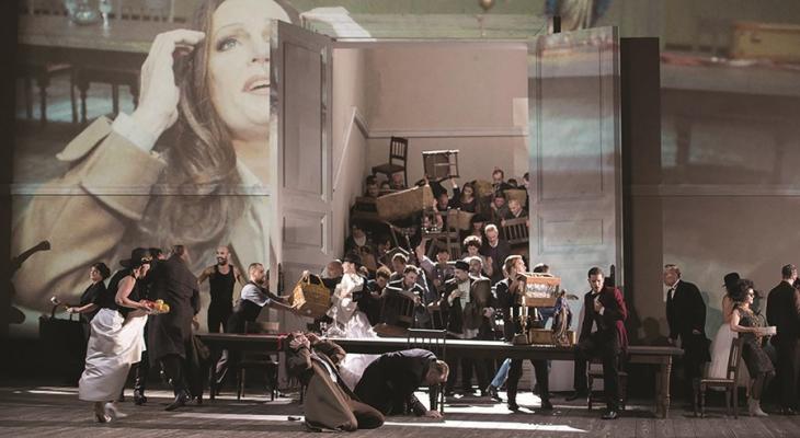 People on stage with a long table and a mountain of furniture in the background