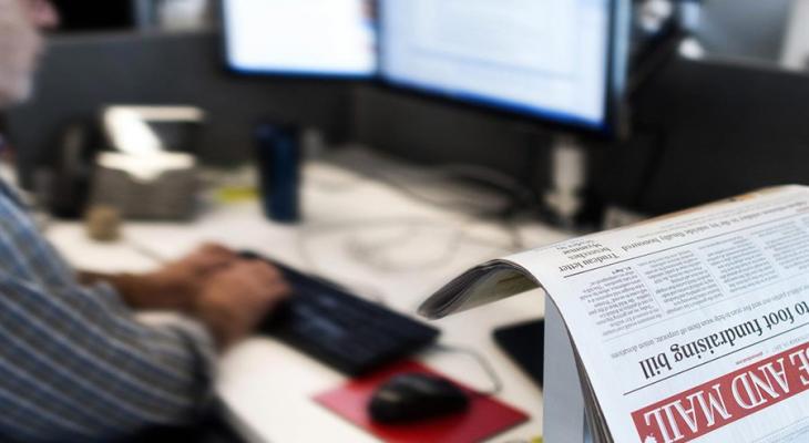 Person typing with copy of The Globe and Mail