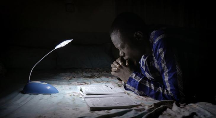 Person reading by a small lamp