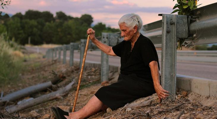 Woman sitting on the ground by the side of the road