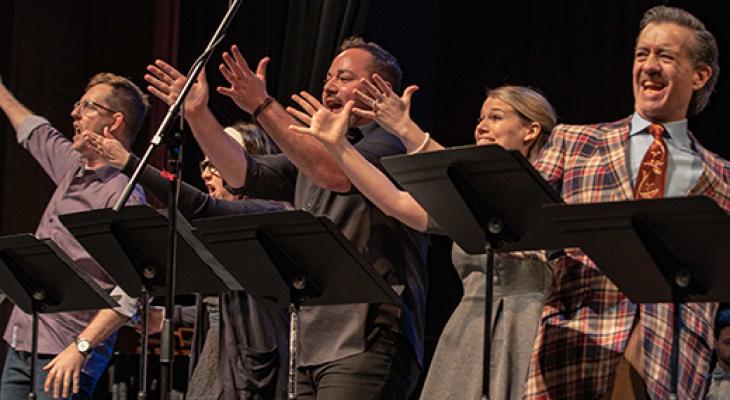 A group of people reach out towards the audience mid song