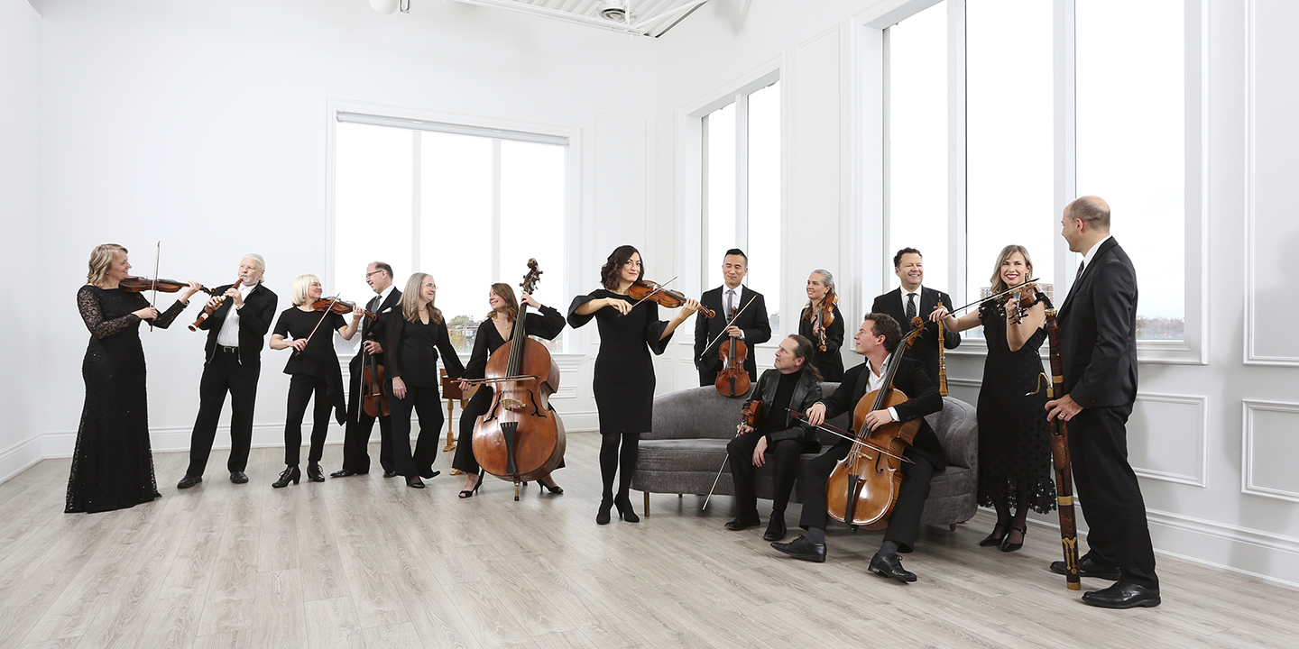 Tafelmusik Baroque Orchestra: musicians standing and playing in a white room