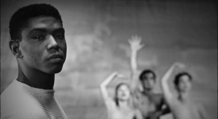 Alvin Ailey looking at the camera in front of three ballet dancers