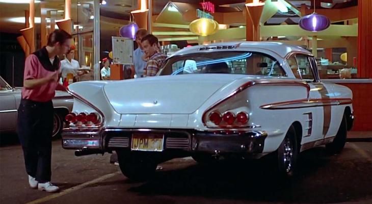 three young men looking at a vintage car