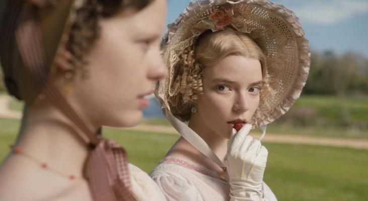 Two women in 19th-century dress. One of them eats a strawberry.