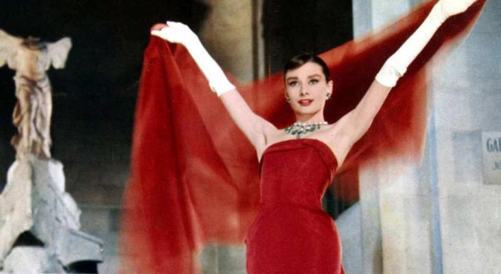 Audrey Hepburn models a red gown and chiffon cape.