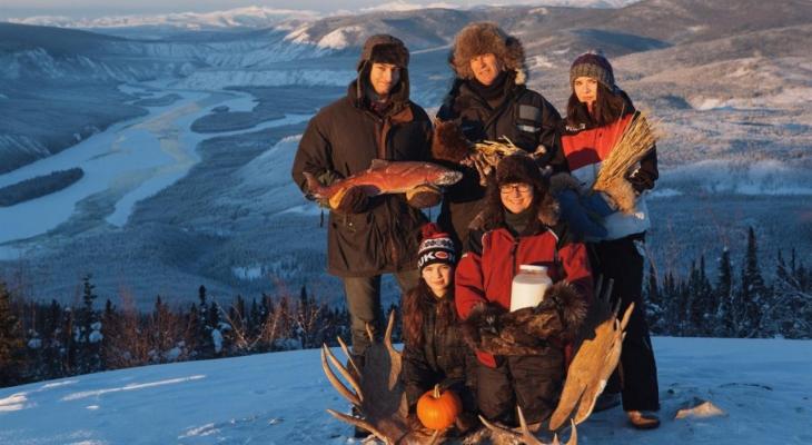 Family holding fish and other foraged food