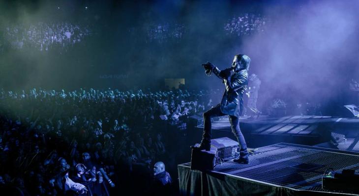 a man with extravagant makeup on singing on stage at a packed concert