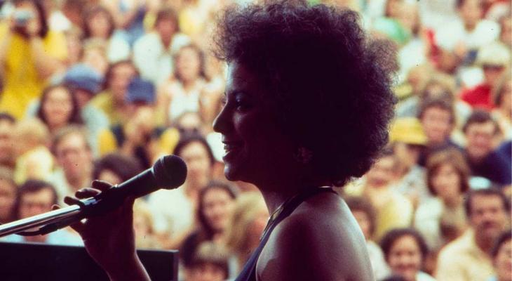a woman holding a microphone on stage in front of a crowd