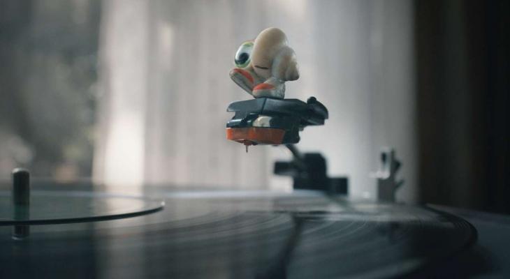 a shell with an eye and sneakers on the arm of a record player