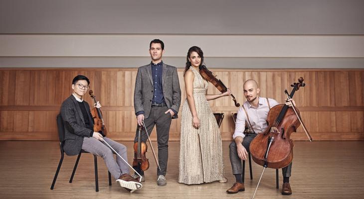 four people standing with musical instruments