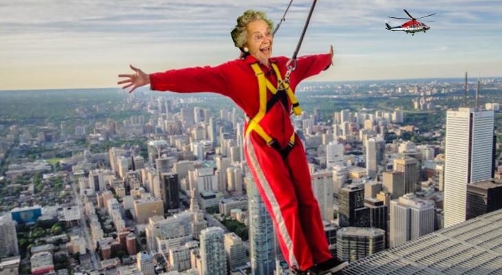 Photoshopped image of an elderly woman leaning out over the edge of the CN tower in a red bodysuit. 