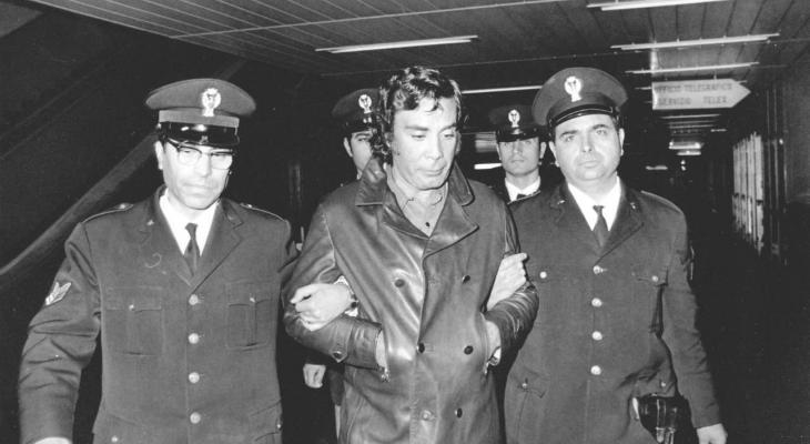 Mafioso, Tomasso Buscetta, is escorted by a policeman on each arm.