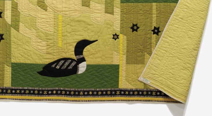 A green quilt with a black loon sewn on