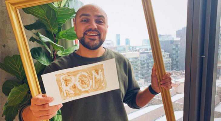 Portrait of host Kiron holding a sign that reads ROM