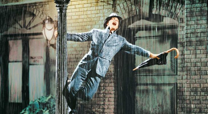 Gene Kelly singing in the rain while holding onto a lamp post