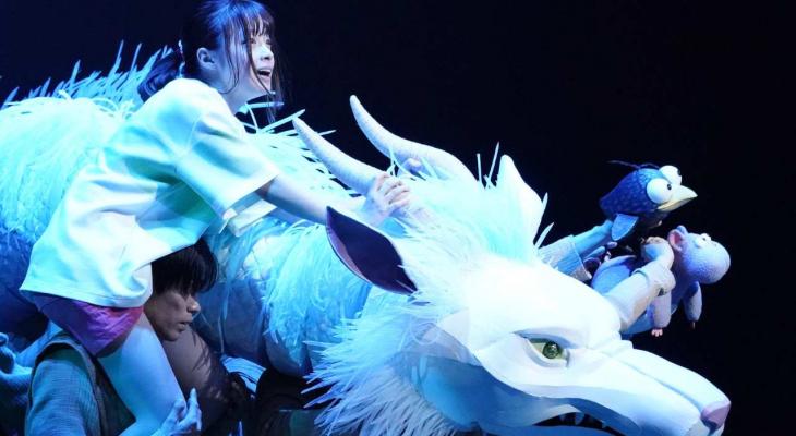 a young girl and a white dragon on stage