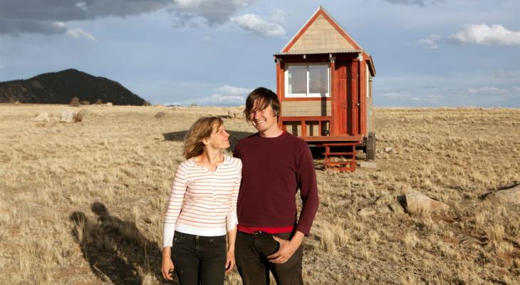 two people standing in front of a tiny house