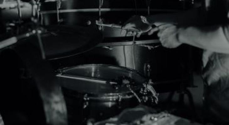 Black and white photo of a drum set and a person's arms playing the drums
