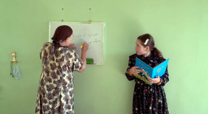 a woman writing on a whiteboard as another woman looks at her
