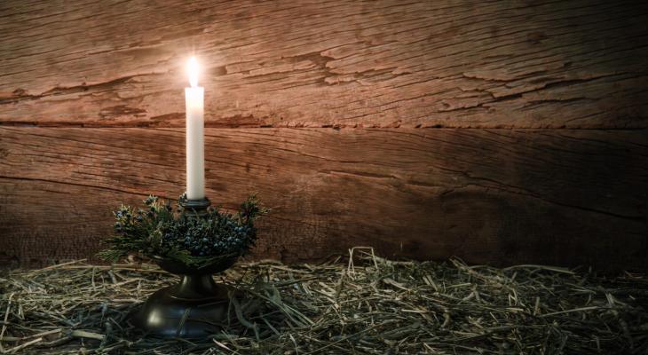 A candle lit on hay