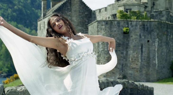 A woman dances in a wedding dress in front of a castle.