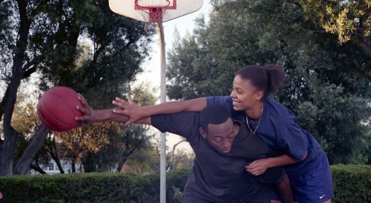 Two players struggle to get possession of the ball on a basketball court.