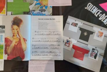 Multimedia display includes concert programs, photographs, graphic t-shirts and sheet music.