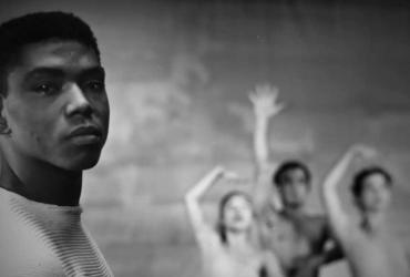Alvin Ailey looking at the camera in front of three ballet dancers