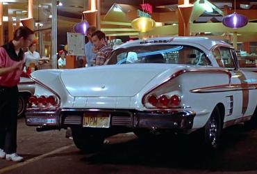 three young men looking at a vintage car