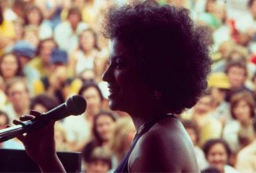 a woman holding a microphone on stage in front of a crowd