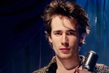 Jeff Buckley with a microphone looking at the camera