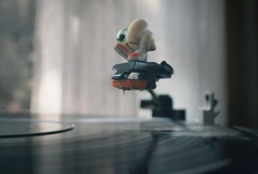 a shell with an eye and sneakers on the arm of a record player