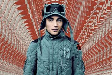 Robert Pattinson in military uniform in front of red patterned fabric