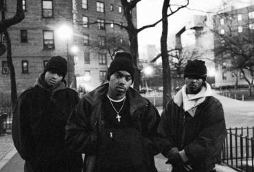 Nas stands with a member of his crew on each side. 