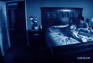 a woman and man in bed pointing at something next to the bed