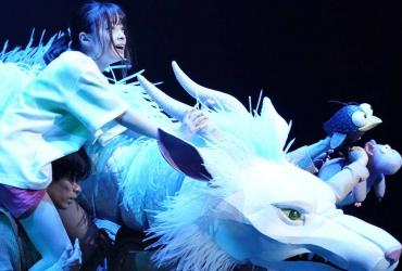 a young girl and a white dragon on stage