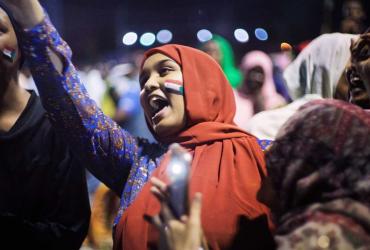 a woman with a flag painted on her cheek surrounded by people