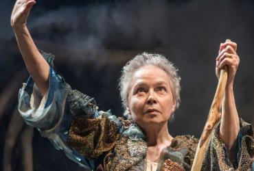 a woman holding a staff and raising her arm in the air