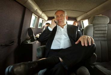 Benjamin Netanyahu talks on his mobile phone in the back of a car.