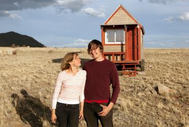 two people standing in front of a tiny house