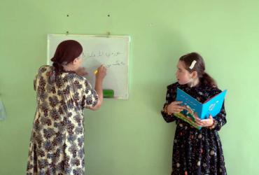 a woman writing on a whiteboard as another woman looks at her