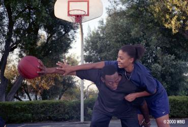 Two players struggle to get possession of the ball on a basketball court.